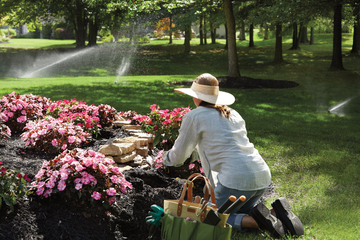Woman gardening while Moen sprinkler runs